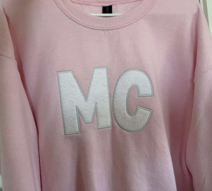 MC — White felt appliqué on pink crewneck