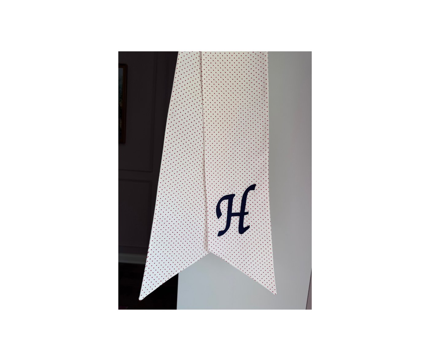 White wreath sash with red pin dots and navy script H monogram
